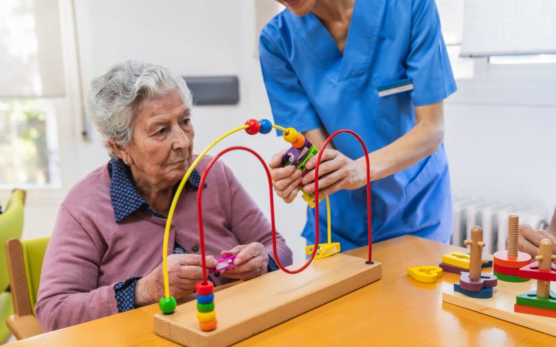 Elderly woman participating in therapeutic activities with a nurse in a geriatric nursing home, focusing on cognitive and motor skills development